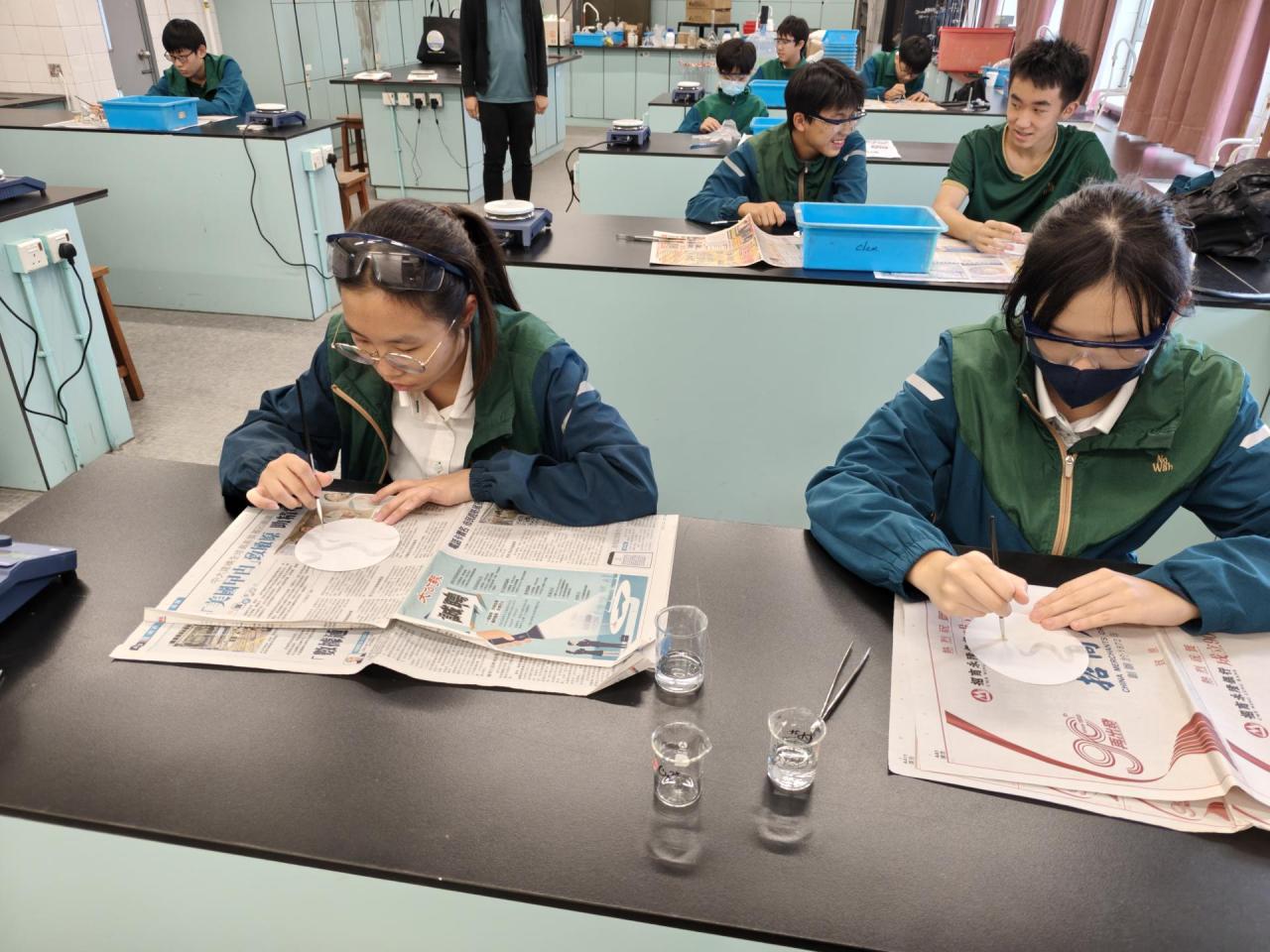 周四聯課活動(科學探索小組)(2025-26) 學生們用檸檬汁在紙上寫字，風乾後無痕，再以電熱板輕烤，字跡便因焦化反應而浮現，如解密般驚喜又有趣。